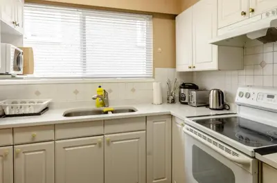 a kitchen with white cabinets and a sink and a window at Convenient Urban Retreat in Vancouver
