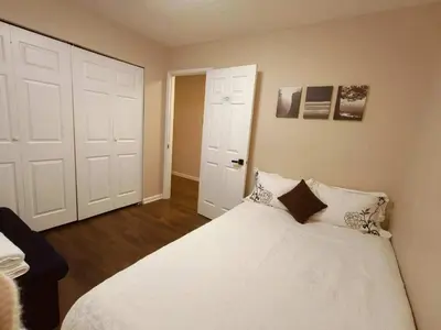 a bedroom with a white bed and two white doors at Convenient Urban Retreat in Vancouver