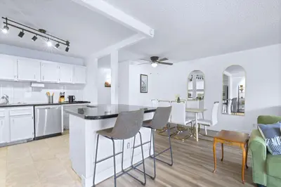 a kitchen with white cabinets and a table and chairs at Stylish Suite at Stampede w Free Parking and AC in Calgary