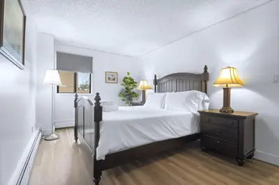 a bedroom with a large bed with two lamps and a dresser at Stylish Suite at Stampede w Free Parking and AC in Calgary