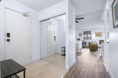 a living room with white walls and a table and a mirror at Stylish Suite at Stampede w Free Parking and AC in Calgary