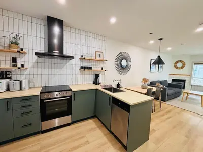 a kitchen with green cabinets and a living room at The OVERLOOK Stay-Mountain View-Free Parking in Canmore