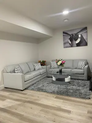 a living room with two couches and a table at Modern suite in basement Upland in Edmonton