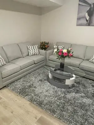 a living room with a couch and a table with flowers at Modern suite in basement Upland in Edmonton