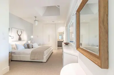 a white bedroom with a bed and a mirror at Premium 4-Bedroom Chalet in Whistler