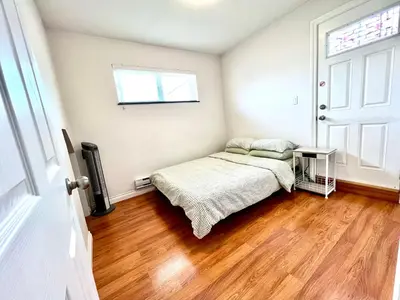 a small bedroom with a bed and a window at Cozy 2-bedroom Private Guest House in a convenient location in Vancouver