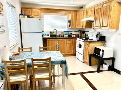 a kitchen with a table and a white refrigerator at Cozy 2-bedroom Private Guest House in a convenient location in Vancouver