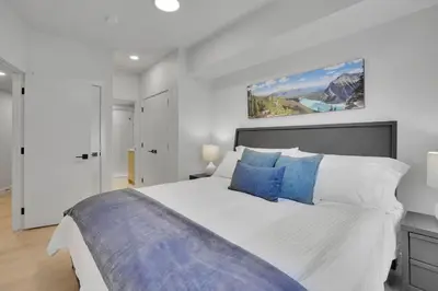 a bedroom with a large white bed with blue pillows at 3 Bedroom with Heated Outdoor Pool and Hottub! in Canmore