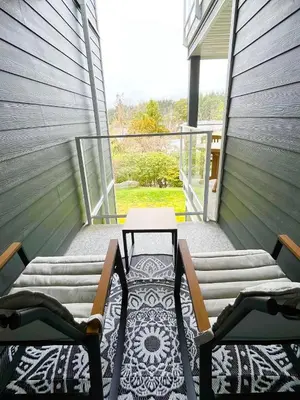a patio with two chairs and a table on a balcony at Old Forest Resort Suite Heated Pool Hot Tub Sauna Beach Vancouver Island in Nanoose Bay