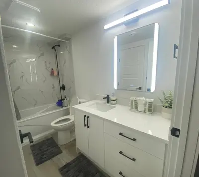 a bathroom with a sink and a toilet and a mirror at Carrington Cozy Suite, Calgary in Calgary