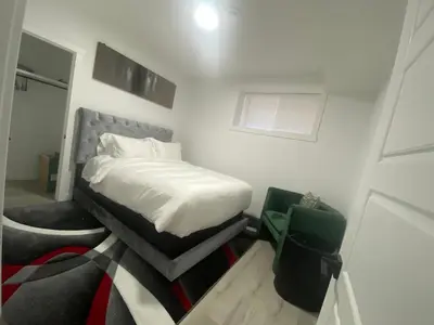a small white bedroom with a bed and a window at Carrington Cozy Suite, Calgary in Calgary