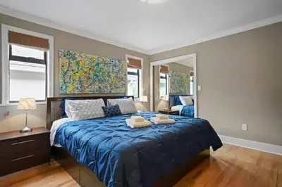 a bedroom with a blue bed with two towels on it at Lovely 2 Bedroom Kits Home - Walk to the Beach in Vancouver