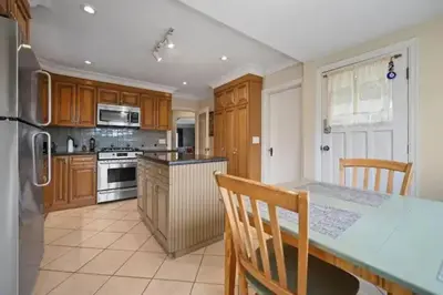 a kitchen with wooden cabinets and a table with chairs at Lovely 2 Bedroom Kits Home - Walk to the Beach in Vancouver