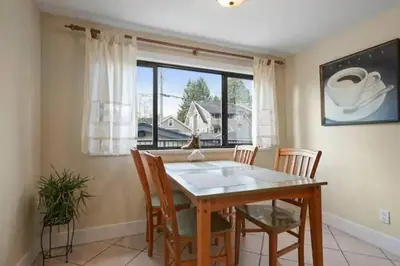 a dining room with a table and chairs and a window at Lovely 2 Bedroom Kits Home - Walk to the Beach in Vancouver