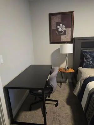 a desk in a hotel room with a bed and a lamp at Cornerstone 4-Bed Home in Calgary