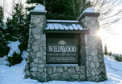 a sign for a wildwood lodge in the snow at 2BR and Loft in Wildwood Lodge, Mountain Views, Close to Ski Hill, Common Hot Tub, Fireplace, Parking in Whistler