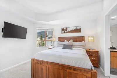 a bedroom with a bed and a tv on a wall at 2BR plus Loft and Sofabed in Tyndall Stone Lodge, Epic Village Location, Mountain Views, Pool and Hot Tub in Whistler