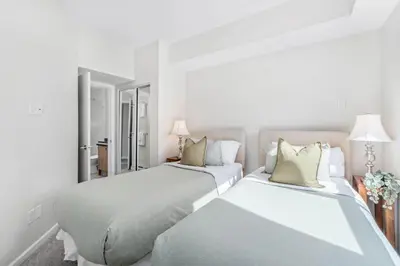 two beds in a white bedroom with two lamps at 2BR plus Loft and Sofabed in Tyndall Stone Lodge, Epic Village Location, Mountain Views, Pool and Hot Tub in Whistler