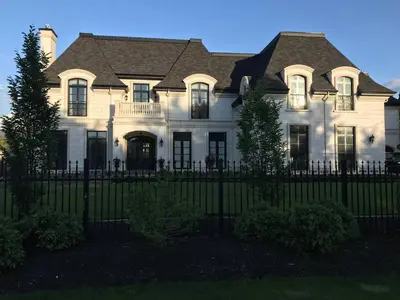 a large white house with a black fence at Chateau Calcaire Carriage House in Kelowna