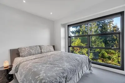 a bedroom with a bed and a large window at The Sunset Lane Waterfront Home in West Vancouver