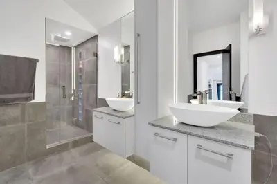 a white bathroom with two sinks and a shower at The Sunset Lane Waterfront Home in West Vancouver