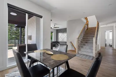 a dining room with a table and chairs and a staircase at Stylish Retreat in Agassiz with Scenic Views in Agassiz