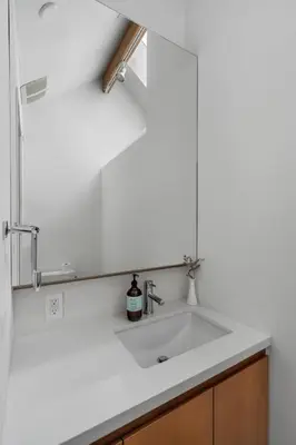 a white sink in a kitchen with a mirror at Beautiful, Newly Renovated Creek Home in Vancouver