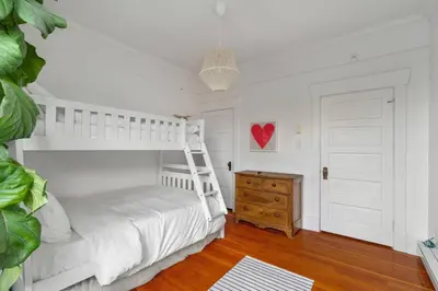 a bedroom with a white bunk bed and a wooden dresser at Beautiful, Newly Renovated Creek Home in Vancouver
