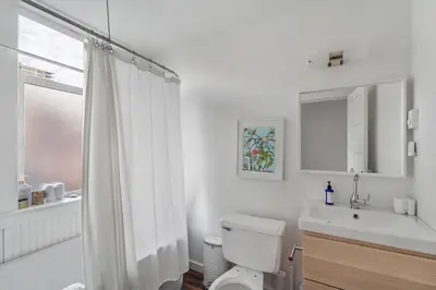 a white bathroom with a toilet and a sink at Beautiful, Newly Renovated Creek Home in Vancouver