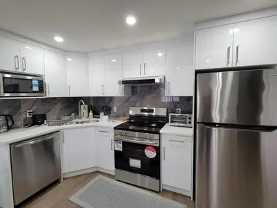 a kitchen with white cabinets and a stainless steel refrigerator at Cozy and Modern Suite - Your Home Away from Home! in Calgary