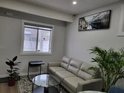 a living room with a couch and a window at Cozy and Modern Suite - Your Home Away from Home! in Calgary