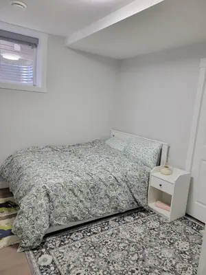 a white bedroom with a bed and a night stand at Cozy and Modern Suite - Your Home Away from Home! in Calgary