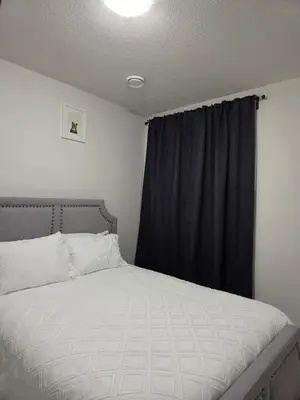 a bedroom with a bed with a black curtain at Elegant & Cozy 2 Bdrm Basement suite near WEM in Edmonton