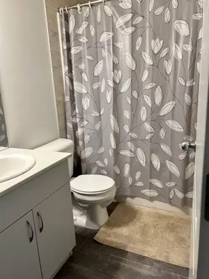 a bathroom with a toilet and a shower curtain at Bedroom in Southwest D in Edmonton