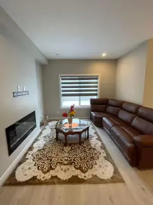 a living room with a leather couch and a coffee table at Brand New Bedroom with private bathroom in Keswick in Edmonton