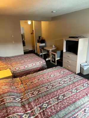 a hotel room with two beds and a table at Fortunes Landing Motor Inn in Enderby