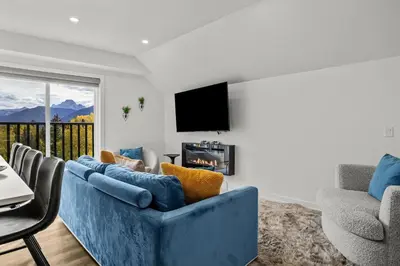 a living room with a blue couch and a tv at Golden Escape 2 Bdrm Mountain VIEWS - managed by Little Sister Getaways in Canmore