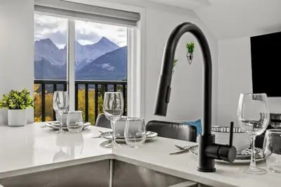 a kitchen with a table with wine glasses on it at Golden Escape 2 Bdrm Mountain VIEWS - managed by Little Sister Getaways in Canmore