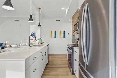 a kitchen with white cabinets and a stainless steel refrigerator at Golden Escape 2 Bdrm Mountain VIEWS - managed by Little Sister Getaways in Canmore