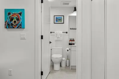 a bathroom with a toilet and a painting of a bear at Golden Escape 2 Bdrm Mountain VIEWS - managed by Little Sister Getaways in Canmore