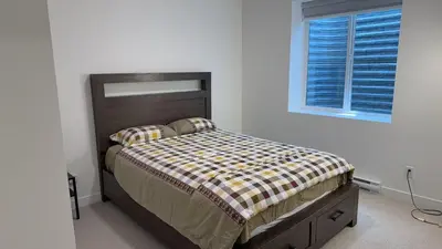 a bedroom with a bed with a wooden headboard and a window at Basement suite -Langley Willoughby in Langley