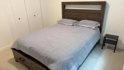 a bedroom with a bed with a wooden headboard and a chair at Basement suite -Langley Willoughby in Langley