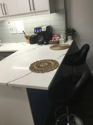 a kitchen counter with two chairs and a rug on it at Almost Heaven - Cozy 2BDRM APT near Heritage Park,Spruce Meadows & Banff-SW Calgary in Calgary