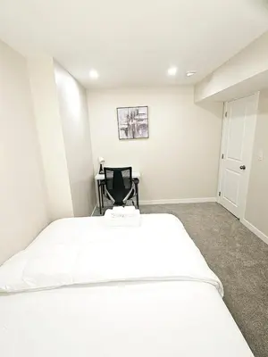 a bedroom with a large white bed and a chair at A Cozy Home away from Home in Edmonton