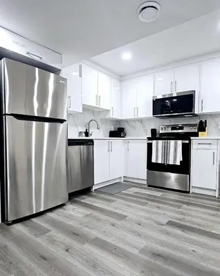 a kitchen with white cabinets and a stainless steel refrigerator at A Cozy Home away from Home in Edmonton