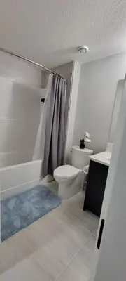 a bathroom with a toilet and a tub and a sink at Cozy 1 bedroom basement suite in Southwest Calgary in Calgary