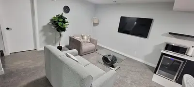 a living room with two chairs and a flat screen tv at Cozy 1 bedroom basement suite in Southwest Calgary in Calgary
