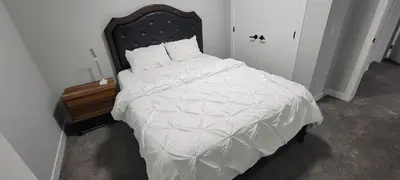 a bedroom with a large white bed with a wooden headboard at Cozy 1 bedroom basement suite in Southwest Calgary in Calgary