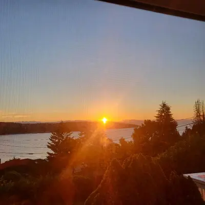 a sunset from a window with a view of a lake at Sea view stay in Lantzville