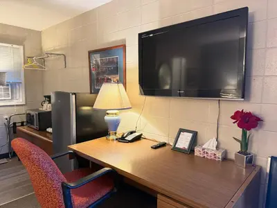 a desk with a lamp and a television on a wall at Athabasca Hillside Motel in Athabasca